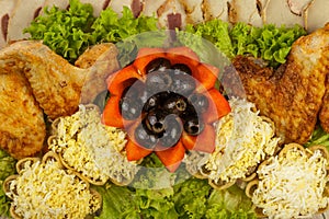 Dish from tartlets and chicken wings with the presence of lettuce leaves.