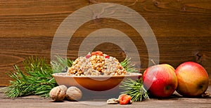 Dish of traditional Slavic treat on Christmas Eve on brown wooden plank. Pine branches, apples, walnuts. Copy space