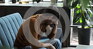 Disheartened Man Sits on Sofa in the Living Room