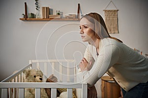disheartened woman standing near crib with