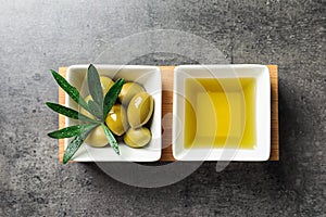 Dishes with olive oil and ripe olives on table