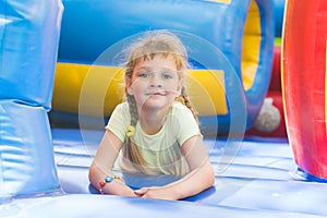 Disheveled five year old girl is playing on big inflatable trampoline