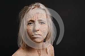 Disheveled woman covered in dry cracked mud