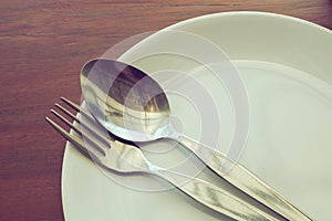 Dishware set on wood table with plate, spoon and fork