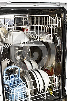 Dishwasher detail. An opened dishwasher with trays extended, lightly loaded. Inside A Dishwasher