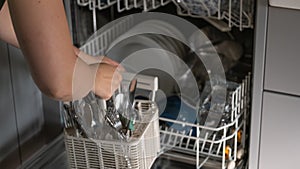 Dishwasher disassembly.Womens hands sort clean dishes from the dishwasher. Plates, forks and glasses in the dishwasher