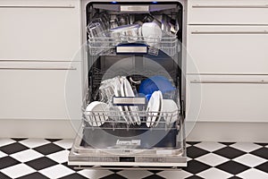 Dishwasher loads in a kitchen with clean dishes photo