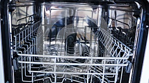 Dishwasher with open door. internal shelves of dishwasher for  distribution of dishes and  basket for cutlery