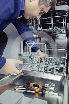 Dishwasher repair. A service center representative diagnoses and repairs a dishwashing machine at home. Specialist in working with