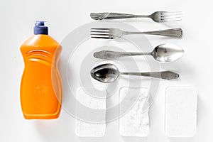 Dishwashing liquid, sponge and tableware on white background top view