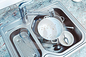 Dishwashing - pile of dirty dishes in kitchen sink