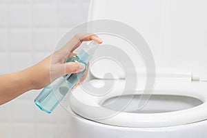 Disinfect, sanitize, hygiene care. people using alcohol spray on toilet seat lid and frequently touched area for cleaning