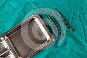 Disinfectant tray for cleaning wounds on a cloth wrapped in green tools.