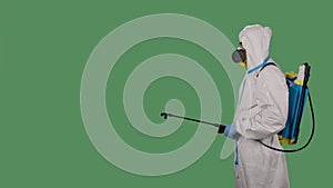 Disinfectant worker in a protective white suit, respirator and glasses makes disinfection on a Green Screen, Chroma Key