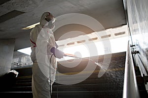 Disinfection of the city. a man in a protective suit cleans the street with a chemical agent, sanitary work