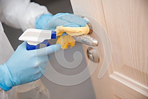 Disinfection and cleaning door handles of house from infection with virus and microbes in biochemical suit. Coronavirus