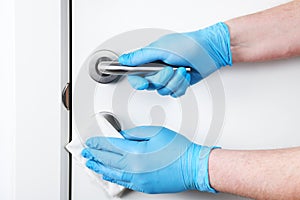 Disinfection in public places, the fight against the virus, coronavirus.Worker`s hand wipes the door handles. A maid or housewife