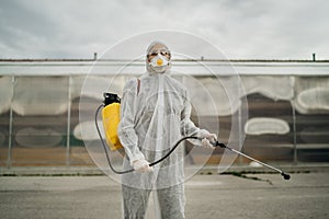 Disinfection specialist in private protective equipment PPE performing public decontamination.Hazmat suit virus protection.