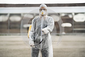 Disinfection specialist in private protective equipment PPE performing public decontamination.Hazmat suit virus protection.