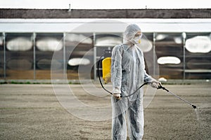 Disinfection worker in private protective equipment PPE performing public decontamination.Hazmat suit virus protection. COVID-19 photo