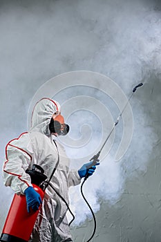 Disinfector in protective suit conducts disinfection photo