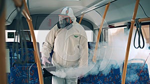 A disinfector sprays a bus during coronavirus pandemic.