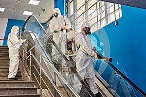 Disinfector wearing protective suits disinfecting stairs with spray chemicals photo