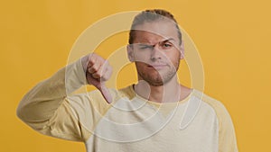 Dislike Concept. Displeased Young Man Showing Thumb Down Gesture Over Yellow Background