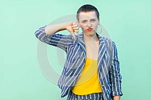 Dislike. Portrait of dissatisfied beautiful short hair young stylish woman in casual striped suit standing with thumbs down and