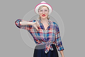 Dislike. Portrait of sad dissatisfied modern stylish mature woman in casual style with hat and eyeglasses standing looking at