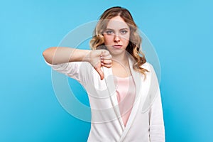 Dislike, unsuccess! Portrait of dissatisfied woman standing with thumbs down gesture. blue background photo