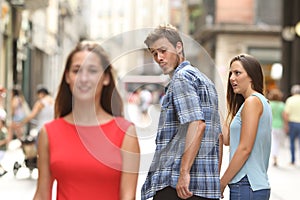 Disloyal man with his girlfriend looking at another girl