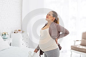 Dismal pregnant woman relieving back pain