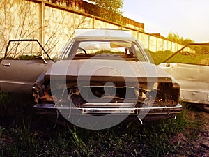 Dismantled an old rusty car on the outskirts of the dump at sunset