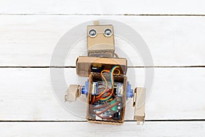 Dismantled robot with hands on white wooden background. flat lay