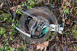 Dismantled smashed television set with plants and weeds growing