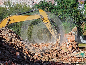 Dismantling a brick building with a bucket excavator