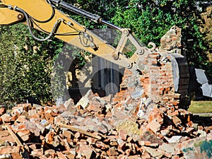 Dismantling a brick building with a bucket excavator