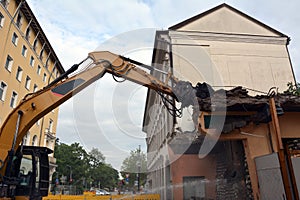 Dismantling by builders of an old building with several floors using an excavator with a manipulator crane. View from below