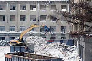Dismantling, destruction of a multi-storey building with the help of a large excavator. The windows are broken