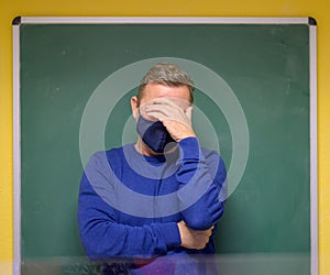 Dismayed male teacher holding his head in his hand photo