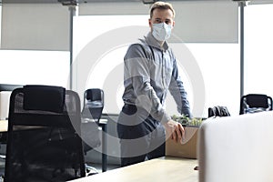 Dismissal employee in an epidemic coronavirus. Sad dismissed worker are taking his office supplies with him from office