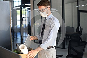 Dismissal employee in an epidemic coronavirus. Sad dismissed worker are taking his office supplies with him from office