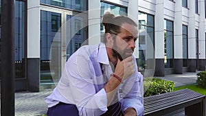 Dismissal and recruitment. An upset employee sits on a bench at a business center with a cortona box and personal items