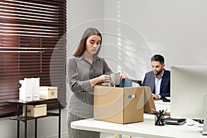 Dismissed woman packing personal stuff into box in office