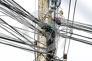 Disorder messy line of black electrical wires on old power pole. Complicated arrangement of electrical cables with a sky