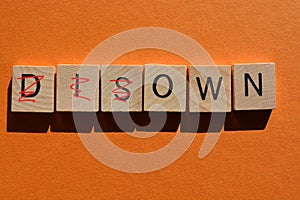 Disown, Own, in 3d wood alphabet letters, isolated on orange coloured background