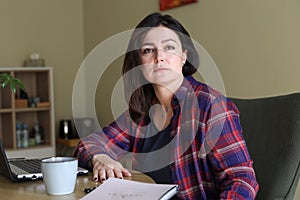 Dispassionate, silent, stressed dark-haired businesswoman working in office with laptop. Frustration and anxiety at work