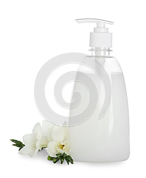 Dispenser with liquid soap and freesia flowers on white background