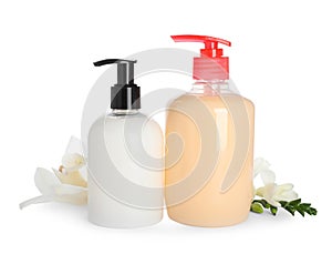 Dispensers with liquid soap and beautiful flowers on white background